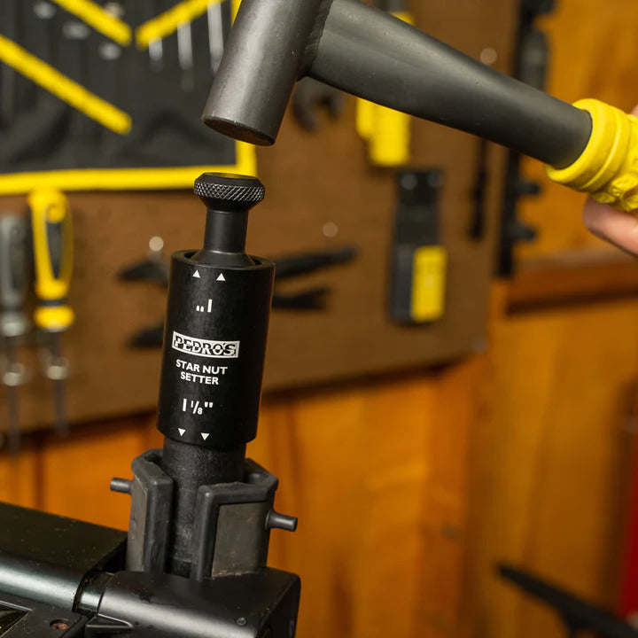 Pedro's Hammer being used to seat a star nut in a bicycle steerer tube with warm wood paneling in the background