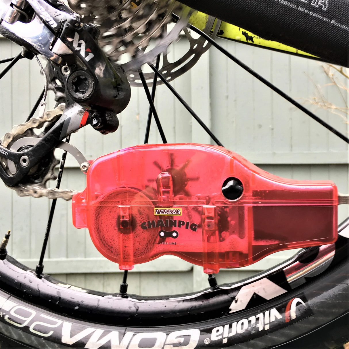 Red Pedro's chain pig being used to clean a chain on a mountain bike with SRAM XX1 11 speed.